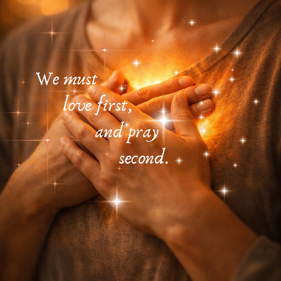Hands held over a person's chest in prayer, glowing lights around the hands, and the words we must love first and pray second.